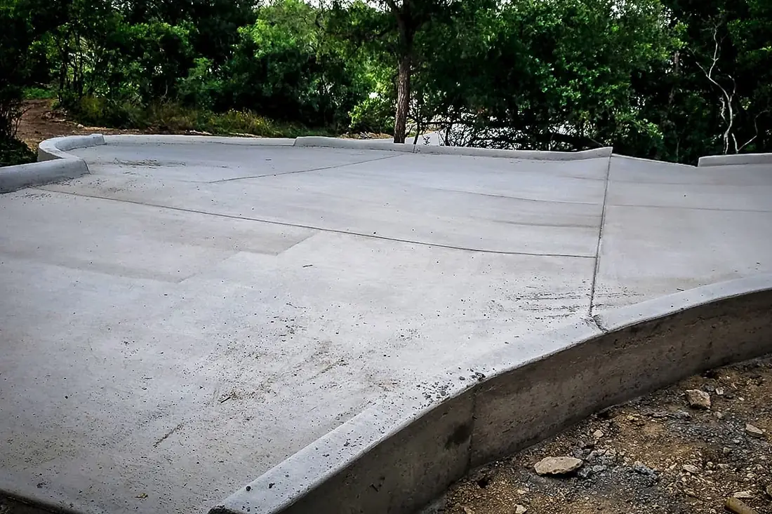 Curbed concrete turnaround poured on a sloped lot near San Antonio