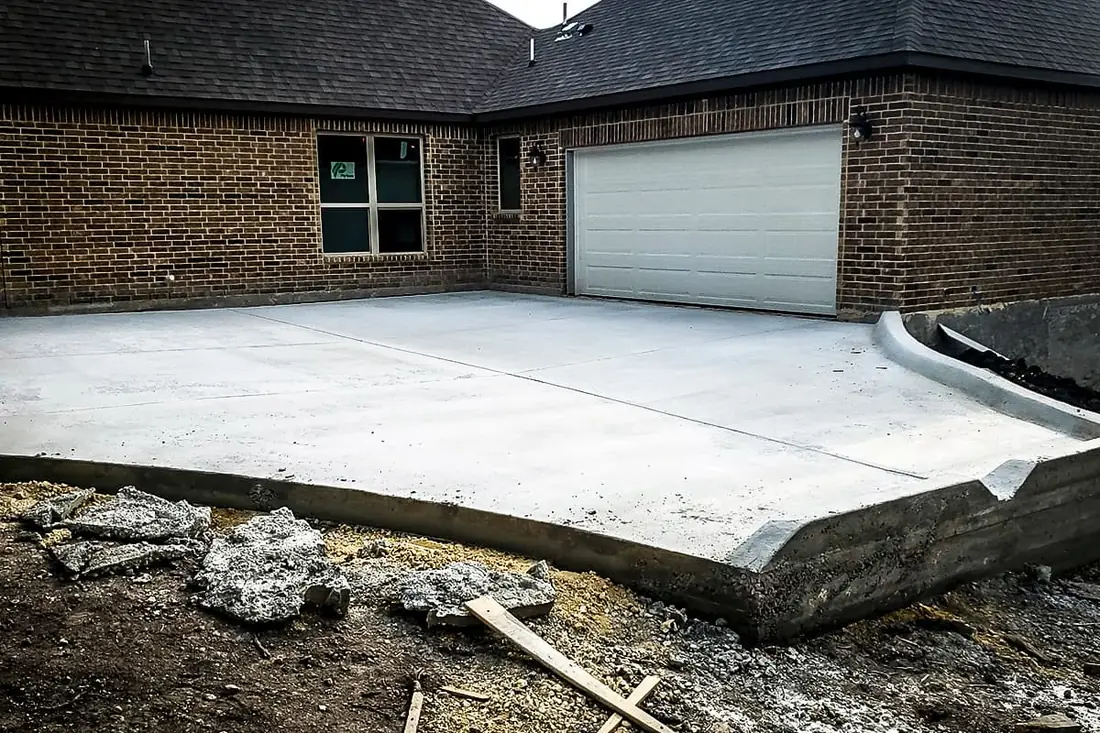 Concrete driveway extension poured alongside a brick home in San Antonio