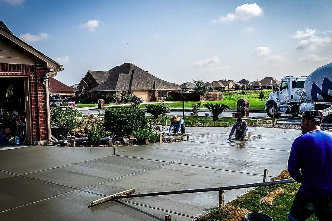 RL Concrete crew floating a fresh driveway pour beside a mixer truck in San Antonio