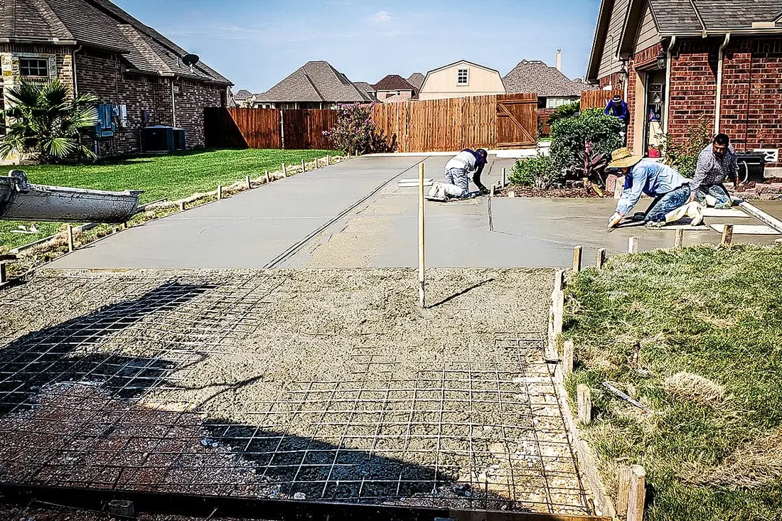 Concrete driveway pour in progress over wire mesh at a San Antonio home