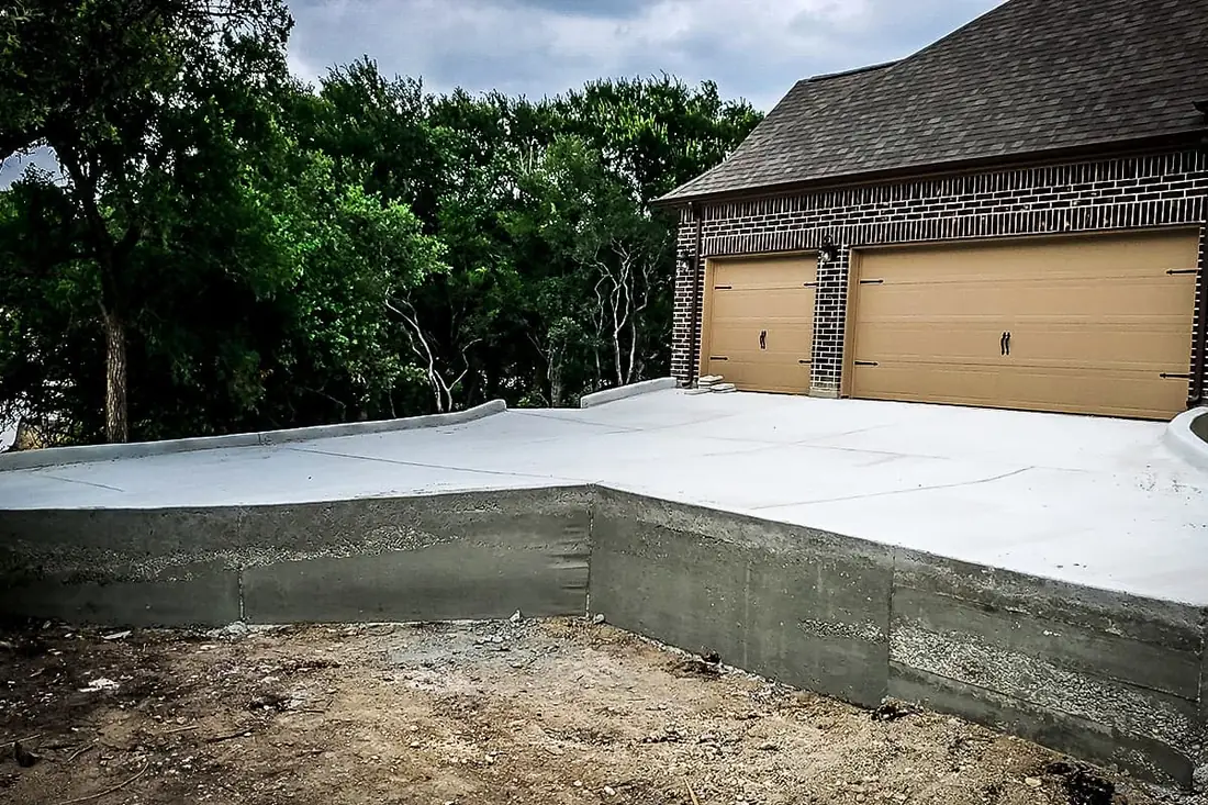Concrete driveway built over a poured retaining wall in San Antonio