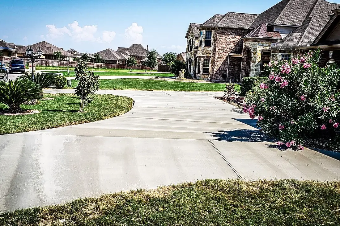 Wide concrete driveway curving to a two-story brick home in San Antonio