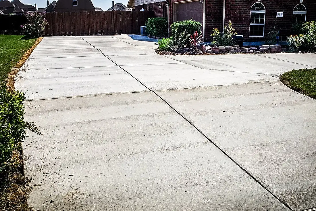 Broad concrete driveway beside a planted bed at a San Antonio home