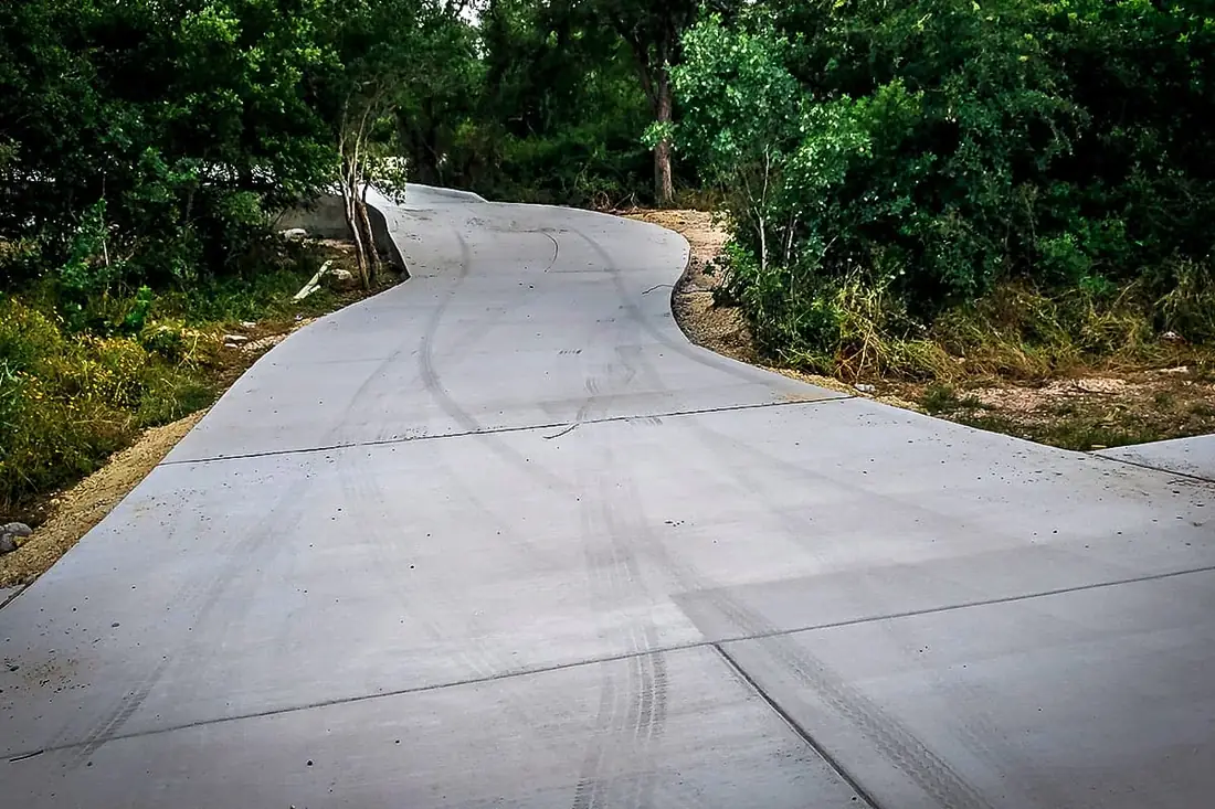 Concrete driveway winding through a wooded lot
