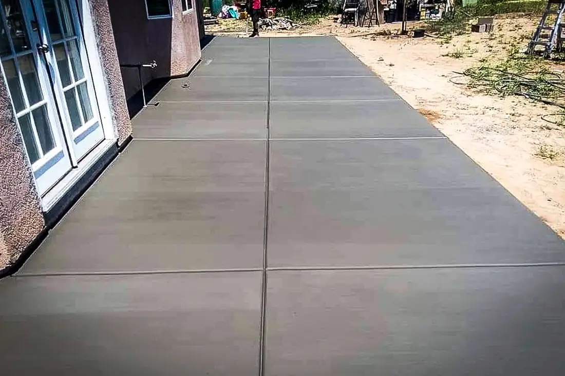 Smooth concrete patio slab poured along the back of a house near San Antonio